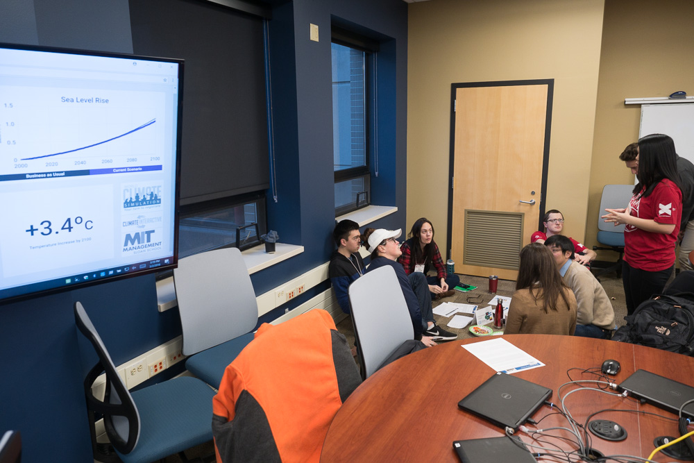 A student group relegated to floor seating--and eventually covered by a blue tarp to symbolize their country's flooding due to sea level rise--considers their options. Photo by Nathan Jandl.