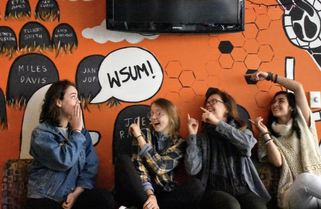 Three women smiling in front of an orange background