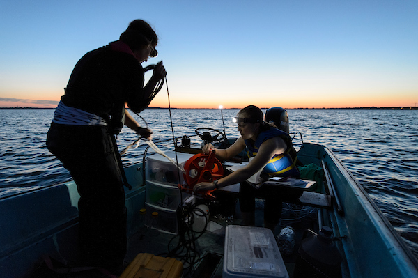 Microbiology graduate student Alexandra Linz, at left, and volunteer Carolyn Voter, a graduate student studying water resources engineering and science, collect data and water samples from Lake Mendota near the University of Wisconsin-Madison campus during a pre-dawn through sunrise summer outing on July 14, 2016. The work is part of a continuous, 44-hour limnology experiment to study how day- and night-light cycles effect growth of water bacteria and carbon exchange between photosynthetic microbes and non-photosynthetic microbes. u0028Photo by Jeff Milleru002FUW-Madisonu0029