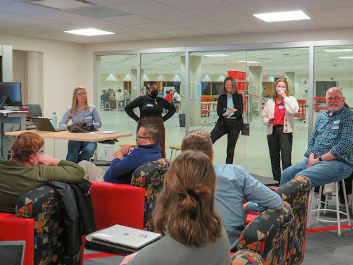 Students stand in a circle during a presentation in an indoor classroom