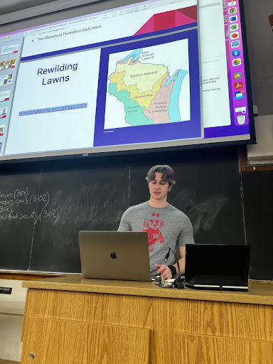 Grady LaJeunesse presents at a podium with a PowerPoint slide showing above his head