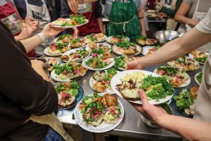 Students plate meals for a dinner service.