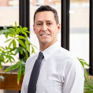 Noah Feinstein standing in front of a window and an indoor plant