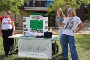 Student representatives from Rewear It pose on front of a poster