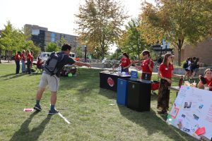 Male student throws an item into the recycling bin in a game