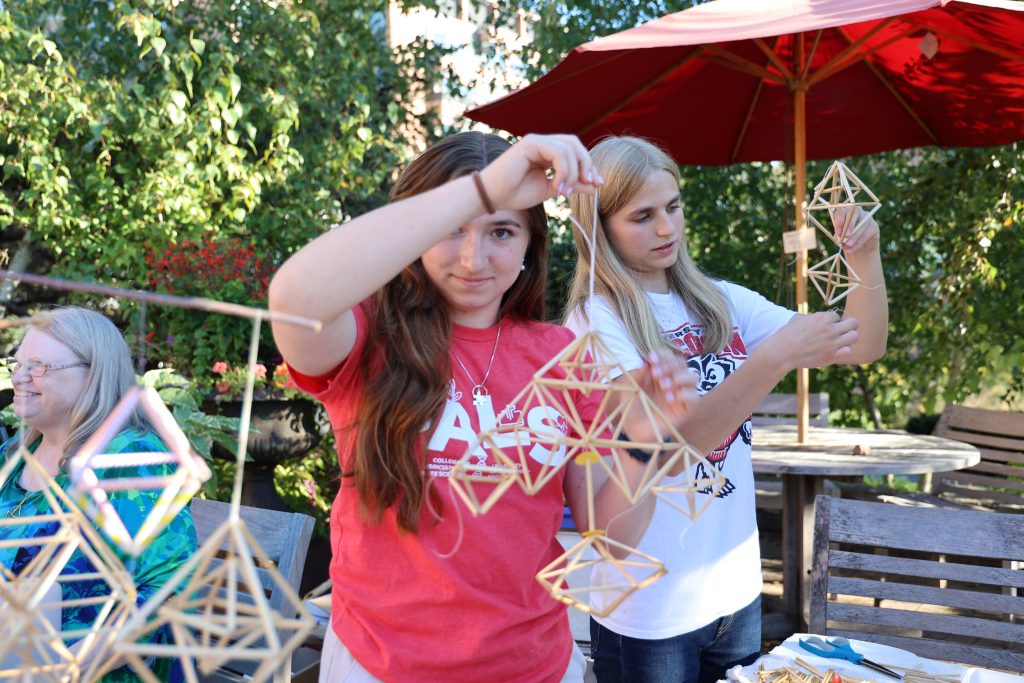 student holds a folk craft and looks directly at camera