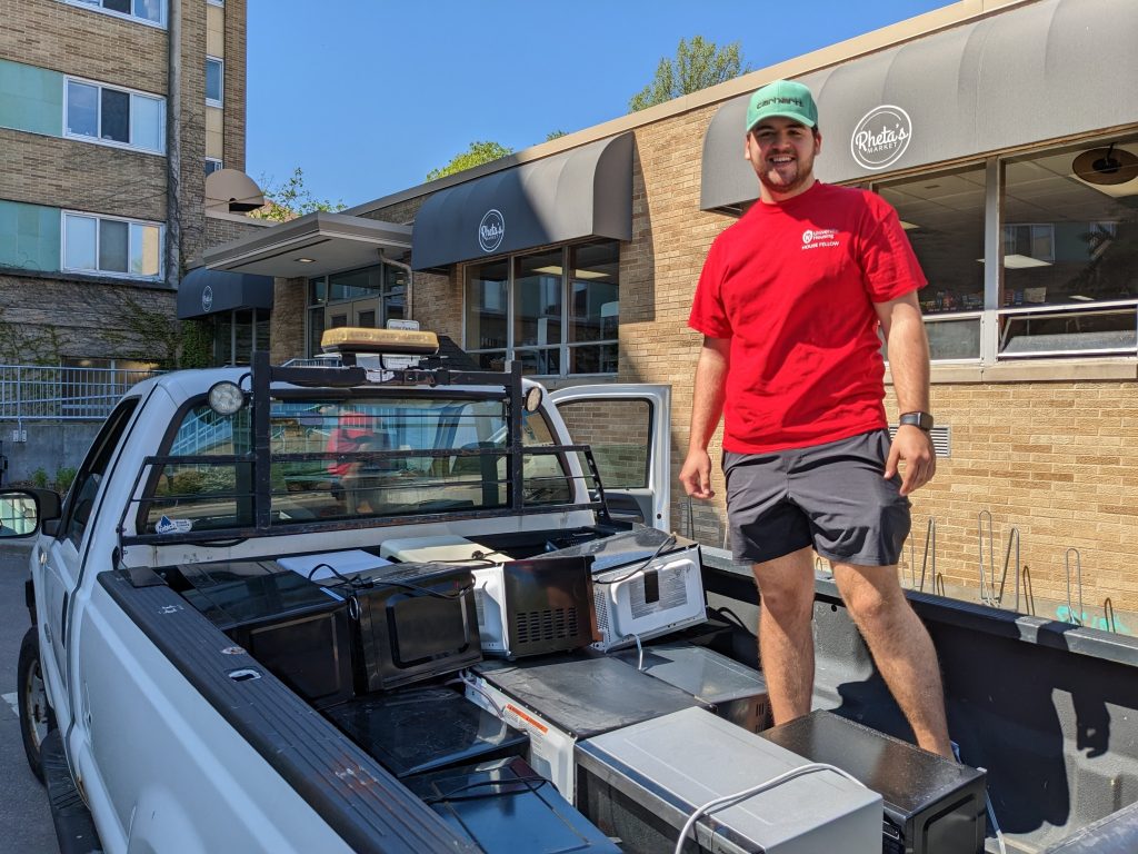Student stands in truck bed full of microwaves
