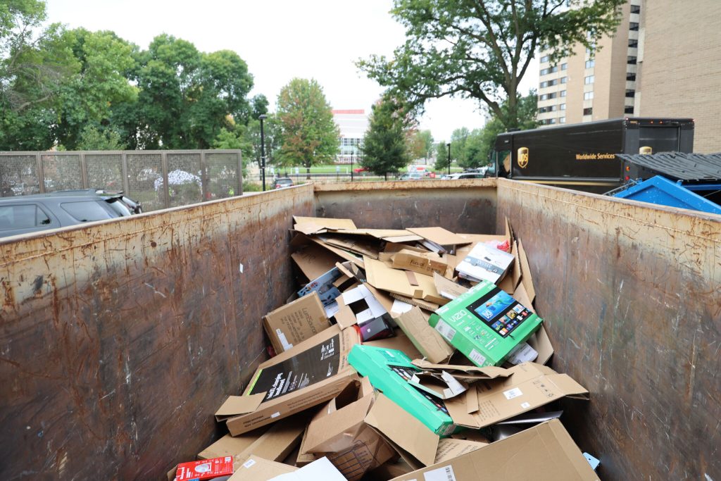 A dumpster full of flattened cardboard boxes.
