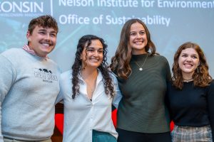 Four young adults stand side by side, smiling