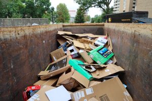 The inside of a large dumpster filled with flattened cardboard boxes to be recycled.