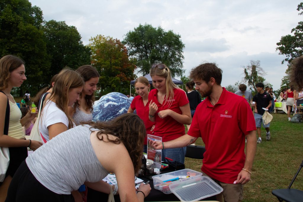 Students and staff making custom buttons at a table.