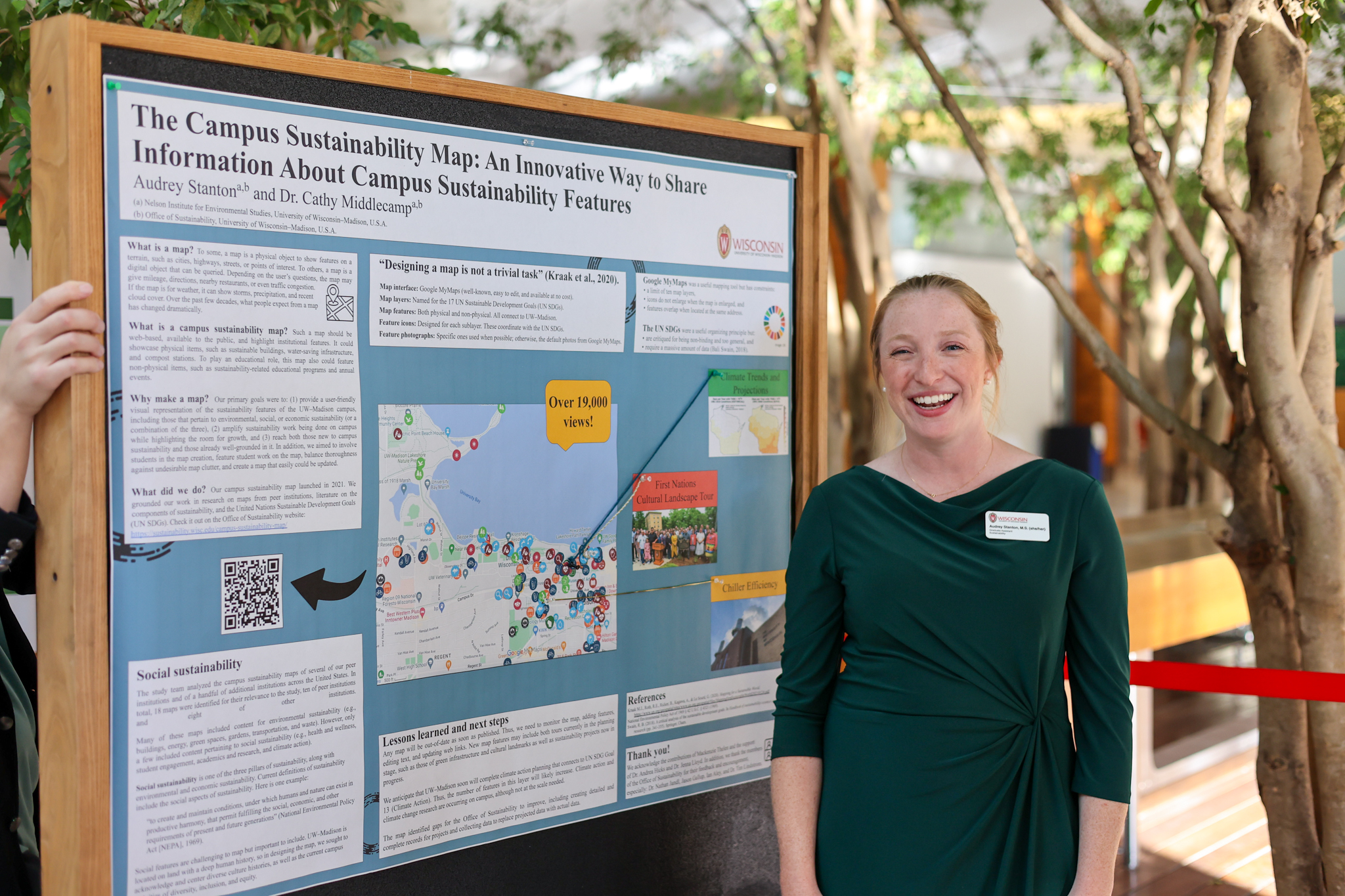 A woman in a green dress stands next to a research poster entitled "The Campus Sustainability Map: An Innovative Way to Share Information About Campus Sustainability Features"